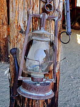 Western style rusty antique broken oil lantern hanging at farm countryside old lamp vintage style hang on wood background.