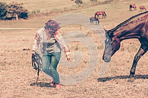 Western woman walking on green meadow with horse