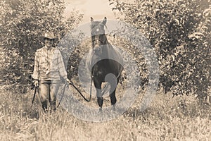 Western woman walking on green meadow with horse