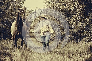 Western woman walking on green meadow with horse