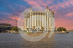 The Westin Hotel along the banks of the blue waters Savannah River with lush green palm trees and tower cranes with blue sky