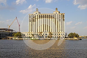 The Westin Hotel along the banks of the blue waters Savannah River with lush green palm trees and tower cranes with blue sky