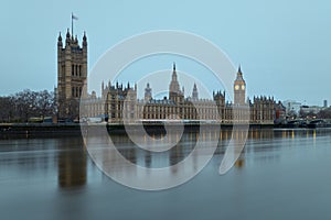 The Westminster Palace and the Big Ben clocktower by the Thames river in London at dawn
