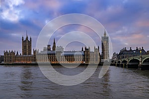 Westminster Palace and Big Ben covered in scaffolding for restoration viewed across the Thames at sunset in London, UK photo