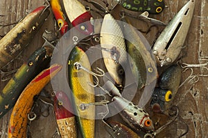 Wet antique fishing lures viewed from above on a rough wood surf