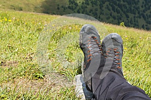 Wet approach shoes and pants drying on the legs of a tourist resting on the green grass