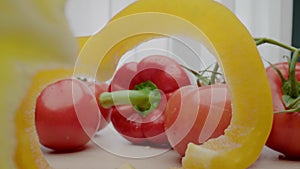 Wet bell pepper and tomatoes lie on table near pepper slices