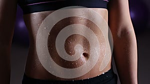 Wet belly of sportive woman covered with water drops, active training in gym