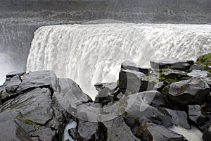 Wet black rocks in front of powerful Dettifoss waterfall, Iceland