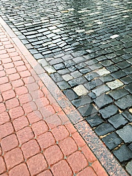 Wet block sidewalk and rough cobblestone road