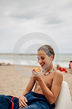 Wet boy looking at apricot on the beach