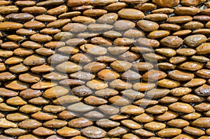 Wet brown pebble stone wall texture