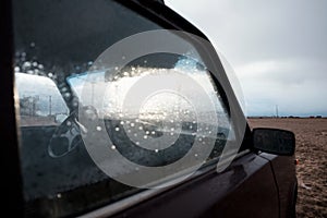 Wet car windshield after rain on sandy beach
