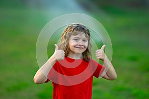 Wet child face. Kid play in garden near irrigation watering sprinkler system. Watering grass with automatic sprinkler