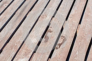 Wet child footprint on brown wooden background