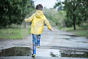 A wet child is jumping in a puddle. Fun on the street. Tempering in summer