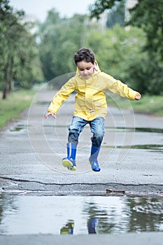 A wet child is jumping in a puddle. Fun on the street. Tempering in summer