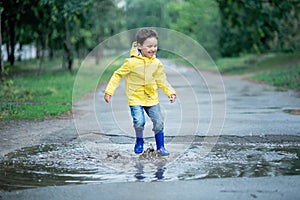 A wet child is jumping in a puddle. Fun on the street. Tempering in summer