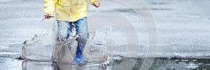 A wet child is jumping in a puddle. Fun on the street. Tempering in summer