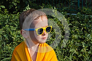 Wet child in sunglasses in a towel