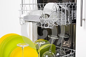 Wet clean dishes in the basket of an open dishwasher