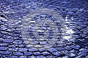 Wet cobblestone pavement after rain, blue color