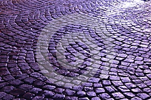 Wet cobblestone pavement after rain, purple color