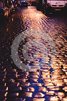 Wet cobblestone road at night.