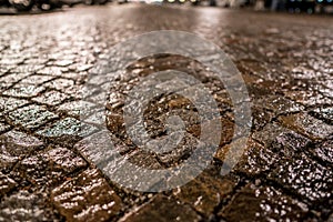 Wet cobblestone urban pavement at night