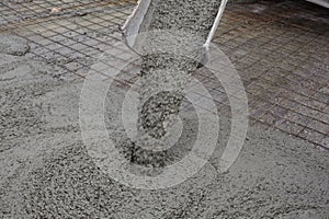 Wet concrete falls from concrete bucket. Industrial construction