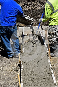 Wet concrete leaves the chute where workers create a footing for a new building.