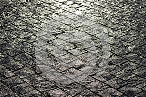 Wet dark basalt paving illuminated by soft light.