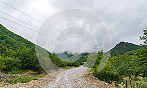 Wet dirt road in mountainous area at cloudy rainy day