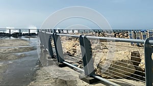 Wet embankment against the background of a not very stormy sea, the waves of which break on the breakwater