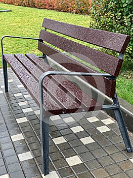 Wet empty wooden bench with rain drops in