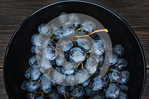 Wet fall grape or mountain grapes in black porcelain bowl