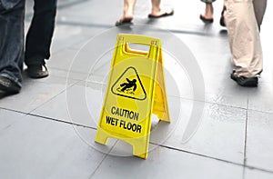 Wet floor sign with people walking in background