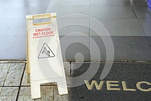 A wet floor warning sign at the entrance of a shopping mall, cleaning concept