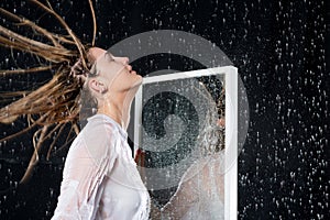 Wet girl with disheveled hair under the spray of