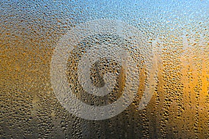 Wet glass. condensation on the window glass. abstract background of yellow and blue colors. large drops