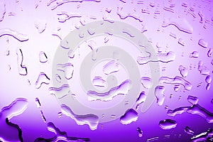 Wet glass in drops of water or rain, bright purple color, studio light, gradient, wet mirror surface texture background close up