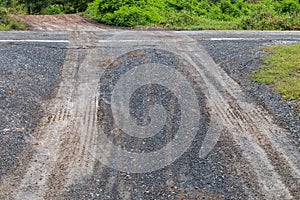 Wet gravel road with car wheel trace.