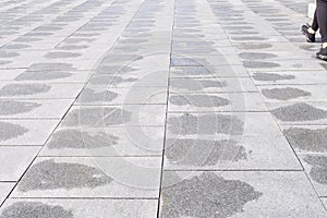 Wet gray pavement after rain. Person`s legs walking aside