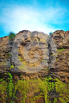 Wet Hard Rock Vertical Cliff with Water Seepage and Blue Sky.