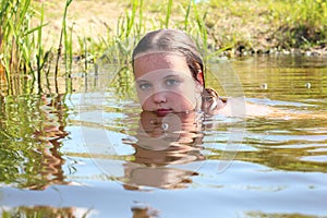 Wet head of a little girl swimming in the overgrown pond