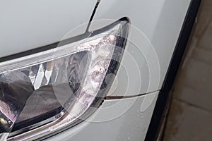 Wet headlight of a white car in the rain