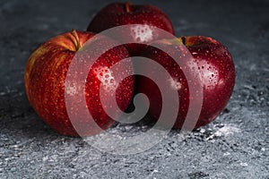 Wet and juicy fresh red apples with water drops on dark background. Selective focus