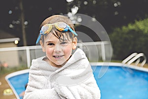 Wet kid on summer swimming pool with towel