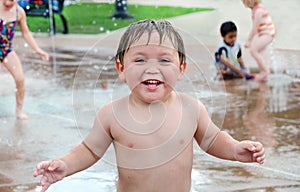 Wet little boy in urban splash pad