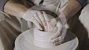 Wet male potter& x27;s hands sculpting soft clay and shaping the pot on potters wheel. Master gives shape to the pottery